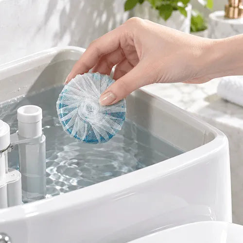 A hand placing a toilet cleaner block into a toilet tank